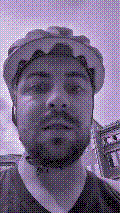 a selfie of a white person, wearing either headphones or a helmet, making an odd expression. the photo is edited to be colorized into a monochrome purple-ish color palette.